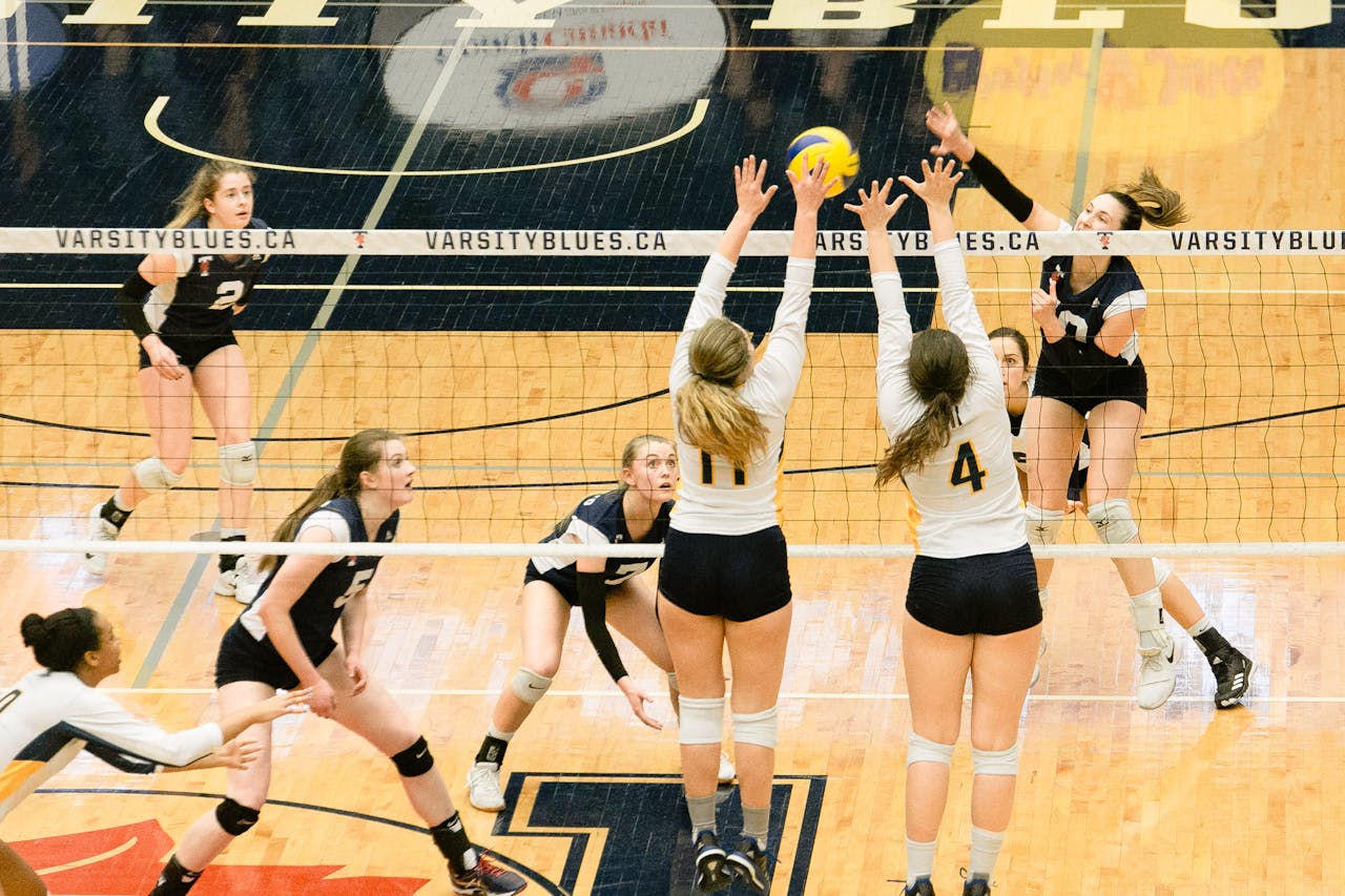 High angle view of women's volleyball game with active players in action on court.